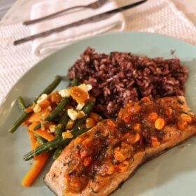 a plate with roasted salmon, green beans and carrots and wild rice.